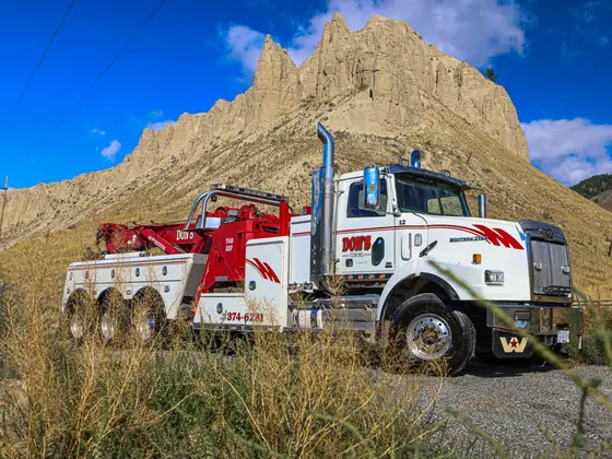 Don's tri-axle heavy wrecker parked in the grass below the hoodoos near Kamloops