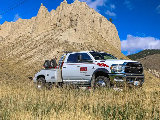 Don's Ram wrecker parked in a field below a sandstone peak