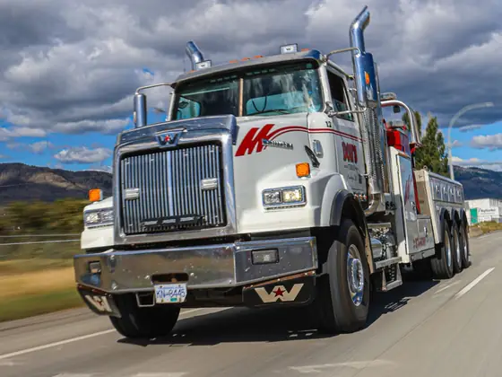 Don's heavy wrecker driving on the highway under summer clouds