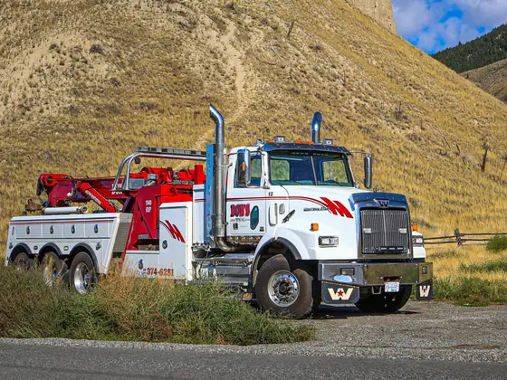 Side view of a Don's tri-axle heavy wrecker on a gravel road
