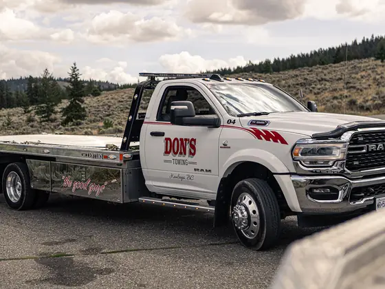 Don's Ram flatbed tow truck parked on a hillside road