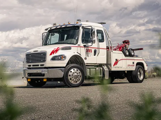 Don's medium-duty wrecker framed by roadside plants