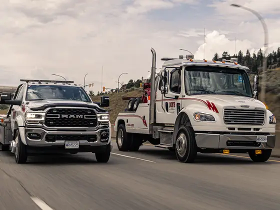 Don's flatbed and medium-duty wrecker driving side by side on the highway