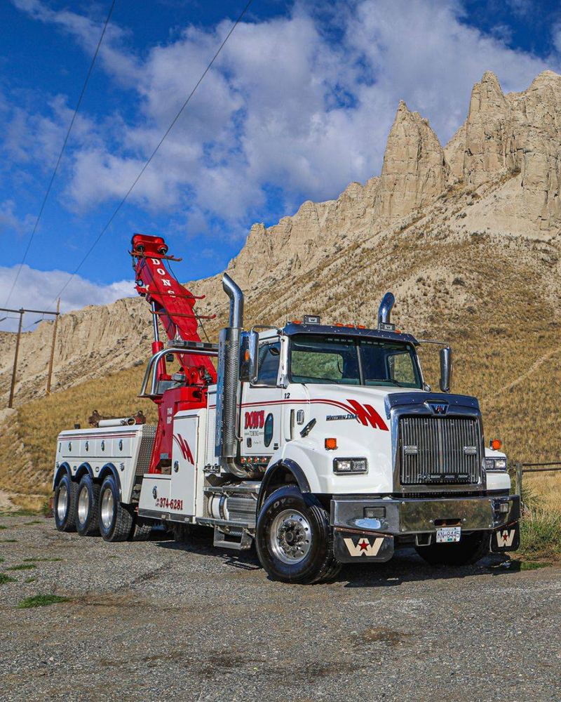 Two of Don's white-and-red tow trucks parked in front of the hoodoos near Kamloops